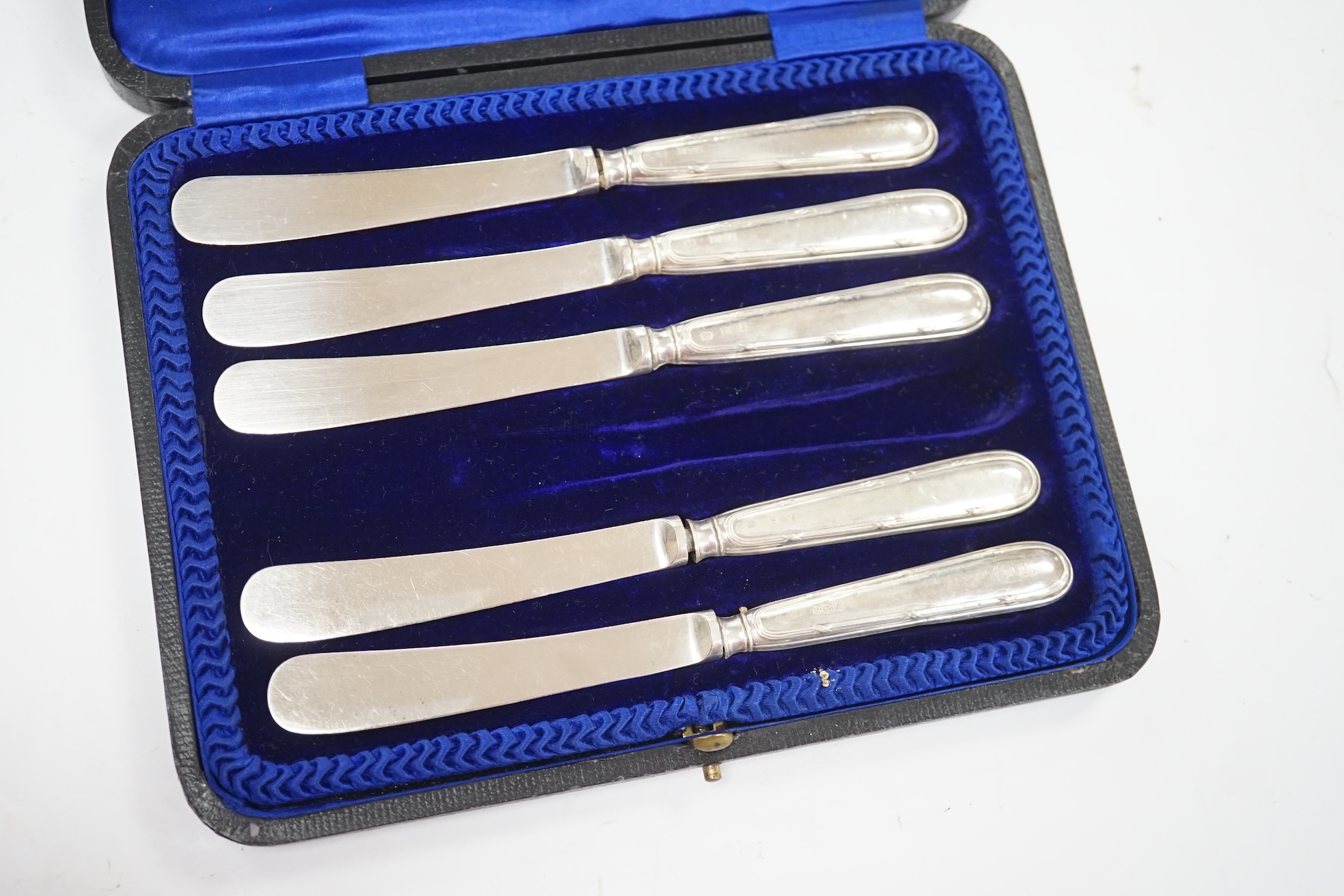 A cased set of six George V silver teaspoons, two cased sets of six silver handled tea knives, fourteen assorted items of 19th century and later silver spoons and a pair of silver sugar tongs. Condition - fair to good